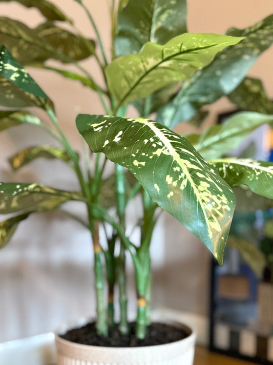Close-up of the Plantish artificial Aglaonema, focusing on the intricate variegation of the green leaves, and the top edge of the decorative cream pot