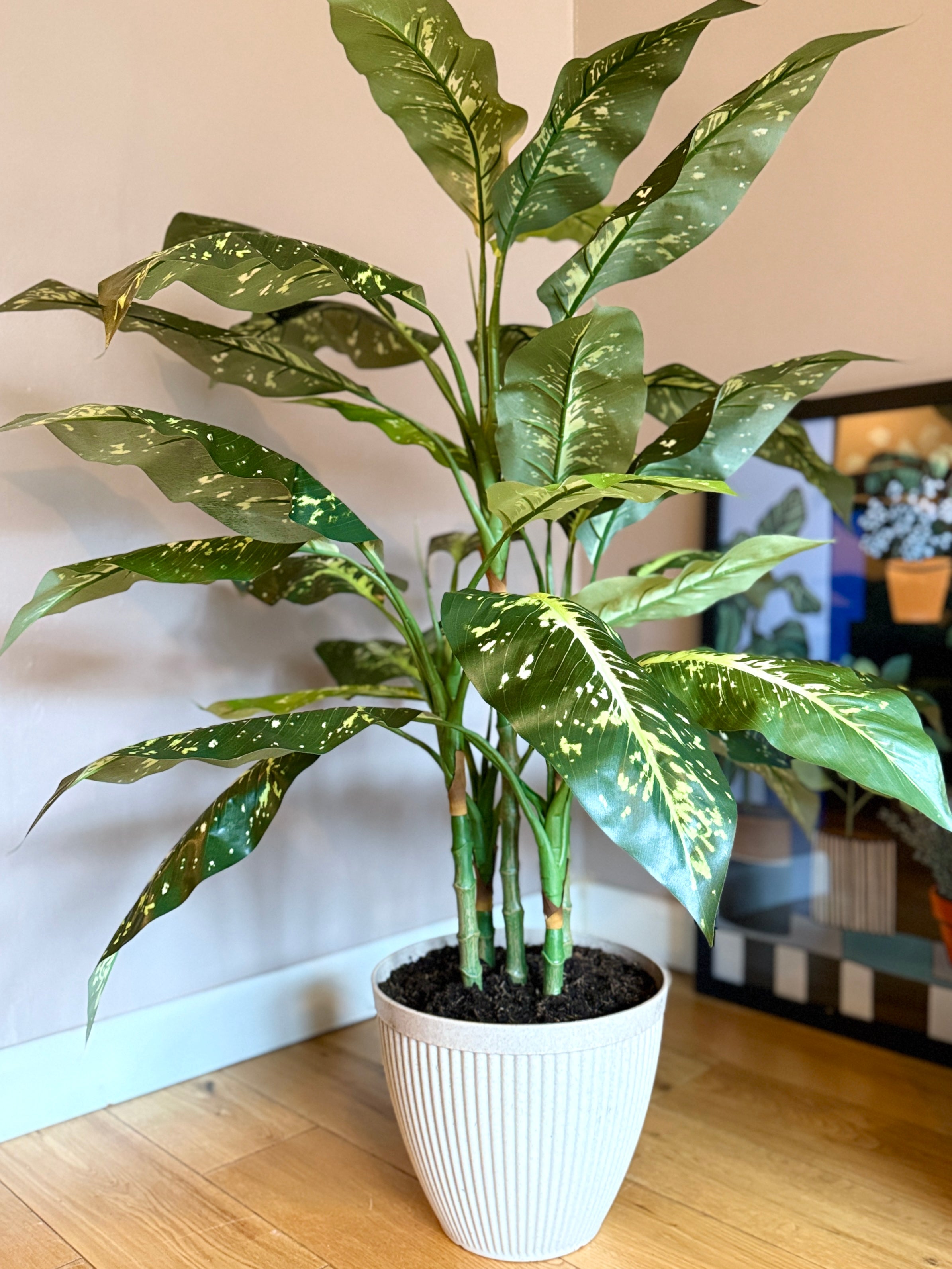 Front view of the Plantish artificial Aglaonema, featuring lush, variegated green leaves, potted in a decorative cream planter with subtle ridged detailing