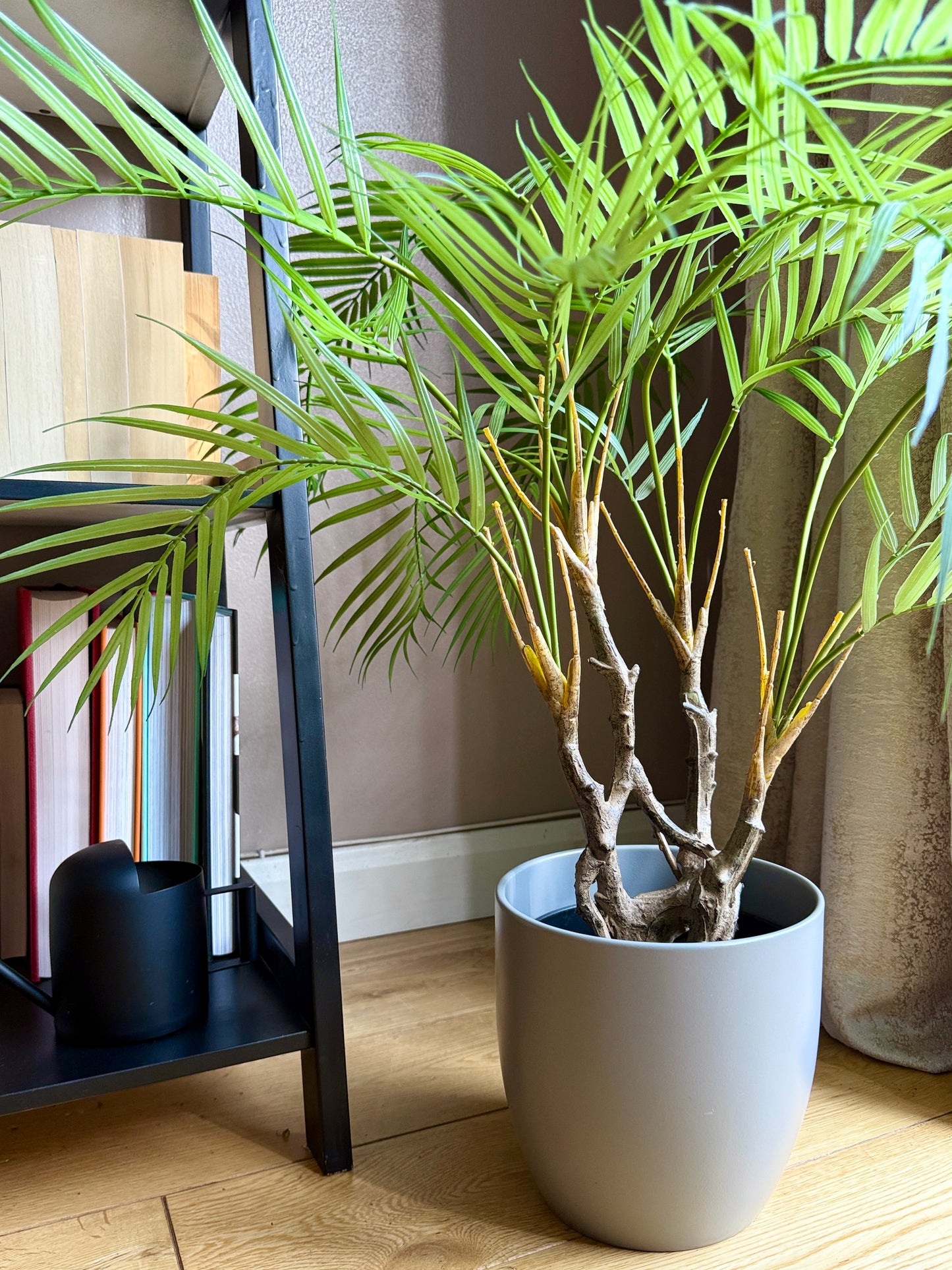 Front view of the Plantish artificial Areca Palm featuring an ultra-realistic twisted trunk and light green fronds, potted in a sleek grey pot. This lifelike plant offers a unique, tropical touch to any room, creating a maintenance-free alternative to real plants.