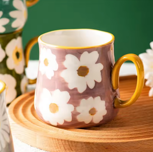 A close up of the Plantish Bright Flower Mug in Pink Gardenia design, shown on a wooden board with a green wall behind.