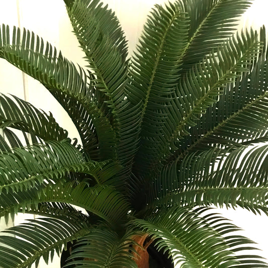 Close up of the Plantish artificial cycas palm, focusing on the ultra-realistic, detailed, dark green fronds, adding elegance to the corner of the room.
