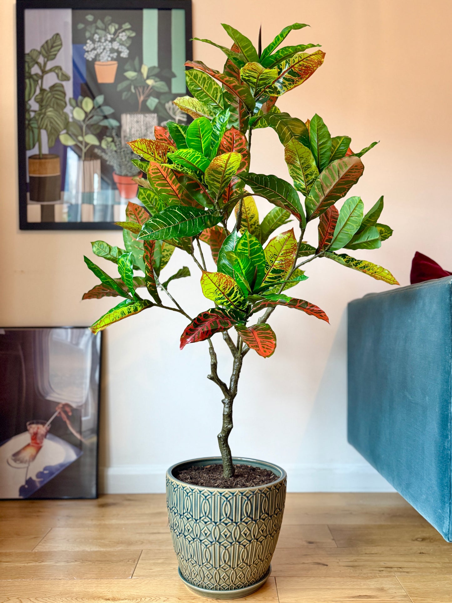 Front view of the Plantish artificial Croton with vibrant dark green, light green, and red leaves, potted in a decorative blue ceramic pot with real soil.