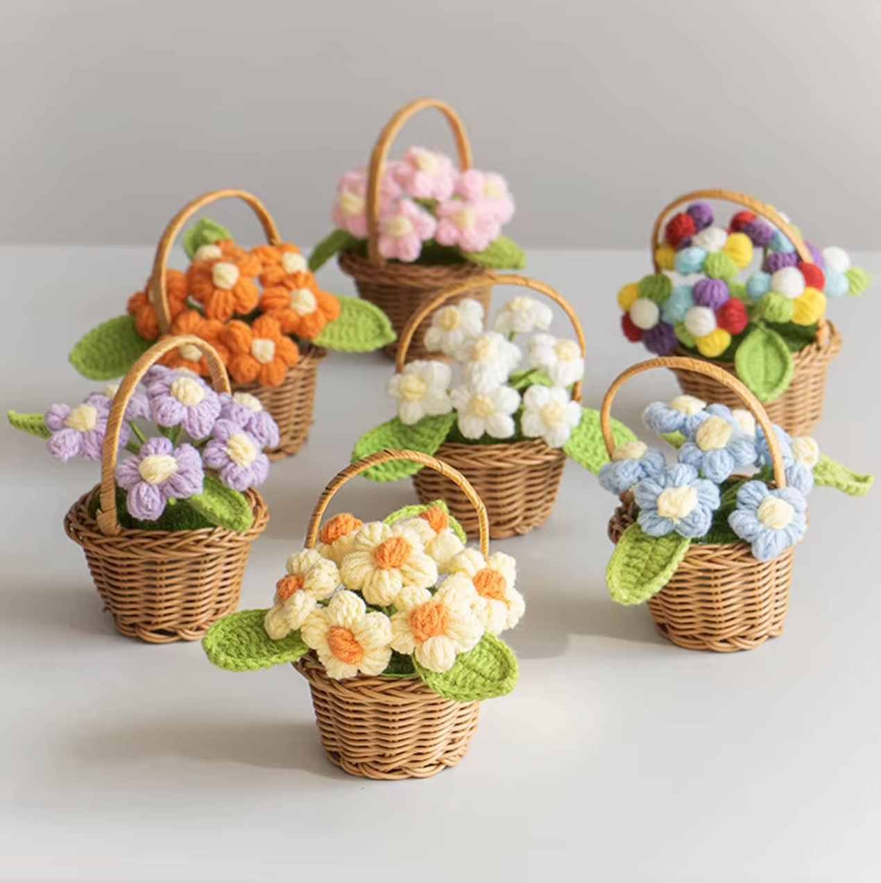 An image of all six Plantish crocheted flower wicker baskes, placed on a white table with a white wall in the background.