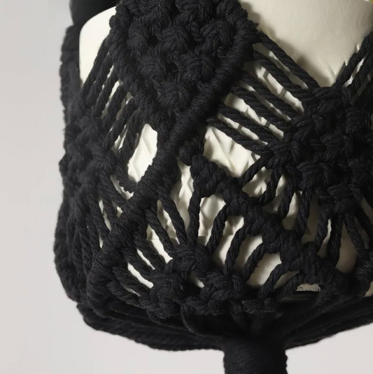 A close up of the Black Plantish Decorative Bohemian Macrame, highlighting the woven design and with a white pot being held by it.