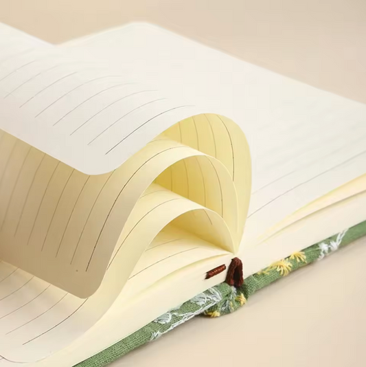 The Plantish Embroidered Wildflower Notebook showing a close up of the lined pages inside, as well as some of the green exterior