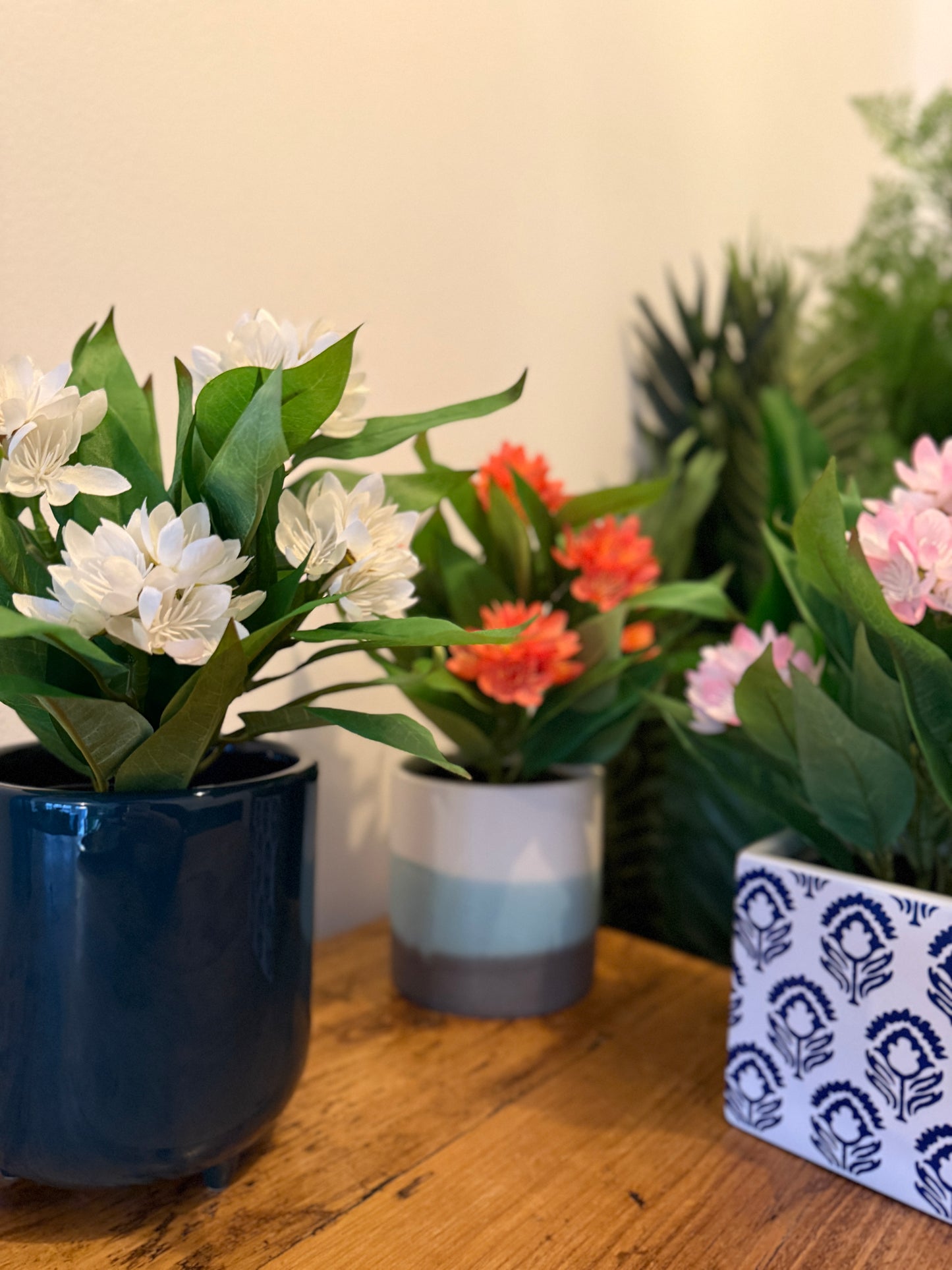 Front view of the Plantish artificial Freesia featuring white, orange, and light pink flowers (left to right) in decorative ceramic pots.
