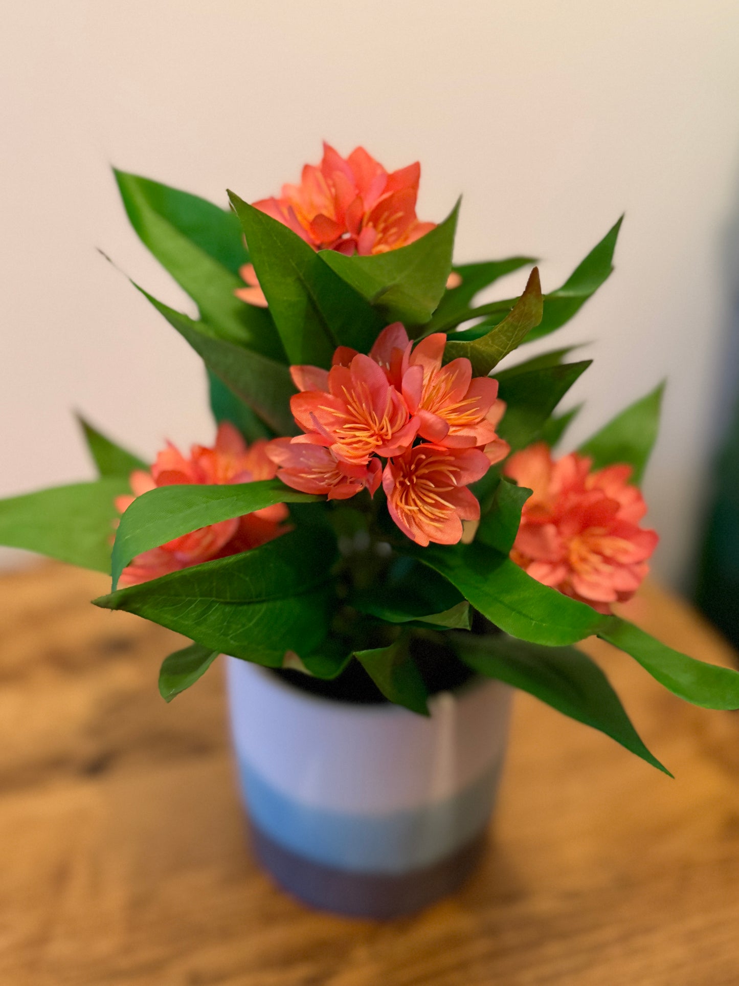 Front view of the Plantish artificial orange Freesia, showcasing its vibrant blooms and detailed green stems. The plant is in an ombre ceramic pot.