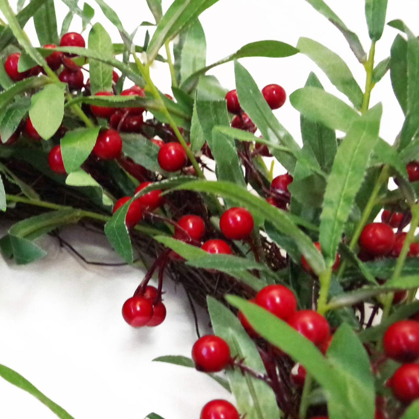 A close up of the Plantish 60cm Festive Mistletoe Wreath, highlighting the deep green mistletoe leaves and red berries in detail.