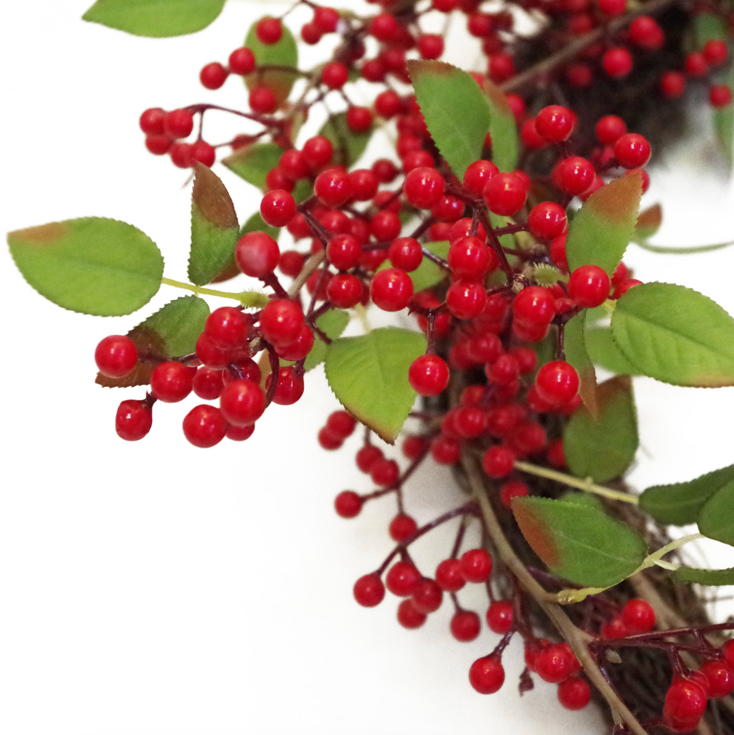 A close up of the Plantish Festive Red Berry Wreath, highlighting the red berries, green leaves, and natural woven ring in detail.