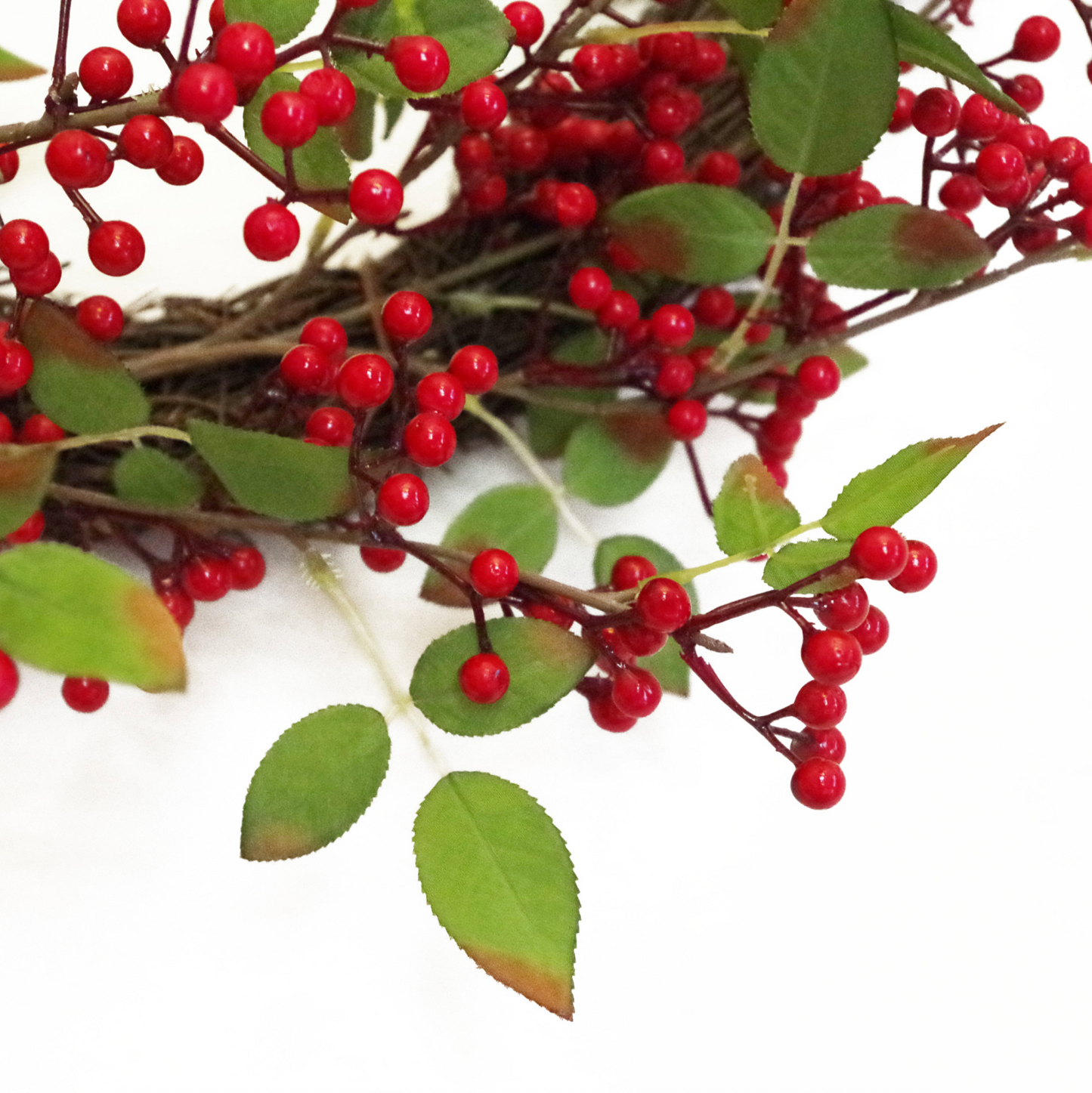 A close up of the Plantish Festive Red Berry Wreath, highlighting the red berries and green leaves, including a realistic brown tinge on some of the leaves.
