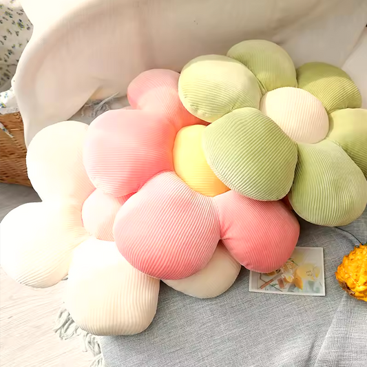 A close up image of three flower plush pillows by Plantish - White/Pink, Pink/Yellow, and Green/White. They are laid out resting on one another.