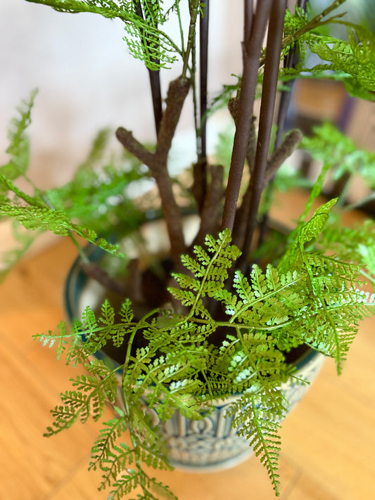 Close up of the large Plantish artificial felce fern, focusing on the vibrant green fronds, deep brown fuzzy stems and the smooth ceramic teal-green pot.