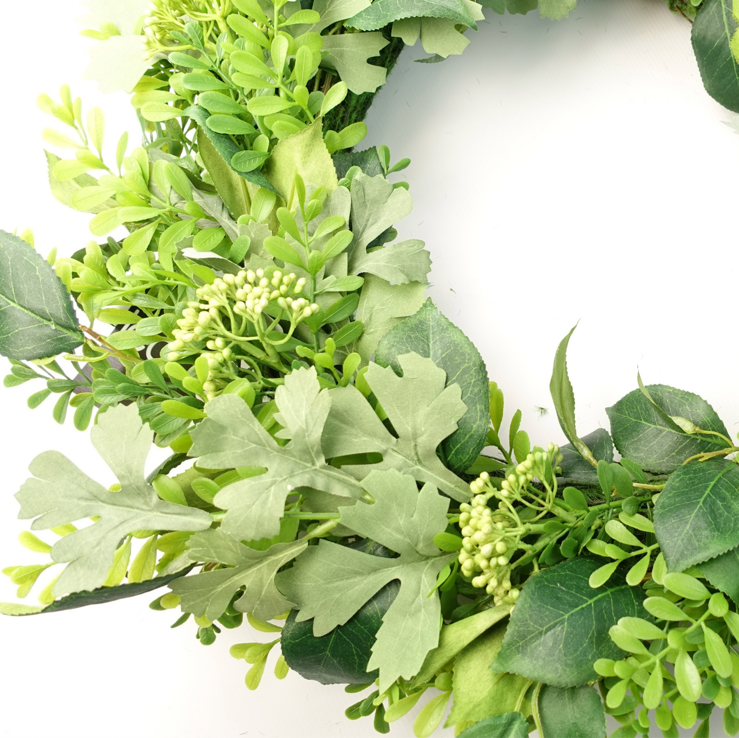 A close up of the Plantish 50cm Lush Green Foliage Wreath, highlighting the mixed green woodland leaves and berries.