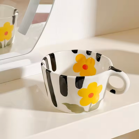 A close up of the Plantish Pinched Mini Mug in the Daisy design. The mug is placed on a white surface with a mirror showing a reflection of the back of the mug.