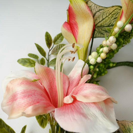 A close up of the Plantish Pink Lily Garland, showcasing the pink and white lily flowers in great detail, as well as the leaves and berries in the background.