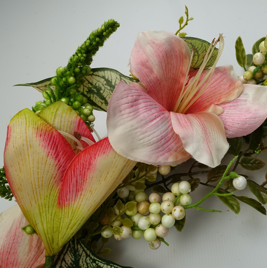A close up of the Plantish 60cm Pink Lily Wreath highlighting the pink lily flowers, variegated alocasia leaves, white berries, and small green leaves.