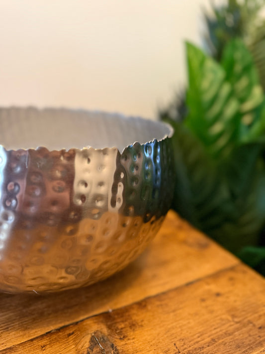 Close up of a large hammered silver-coloured metal planter, highlighting its textured surface.