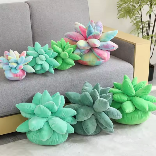 The Plantish Succulent Plush Cushion shown in four colours and two sizes. Some are on a grey sofa and some are on a grey rug on the floor of a living room.