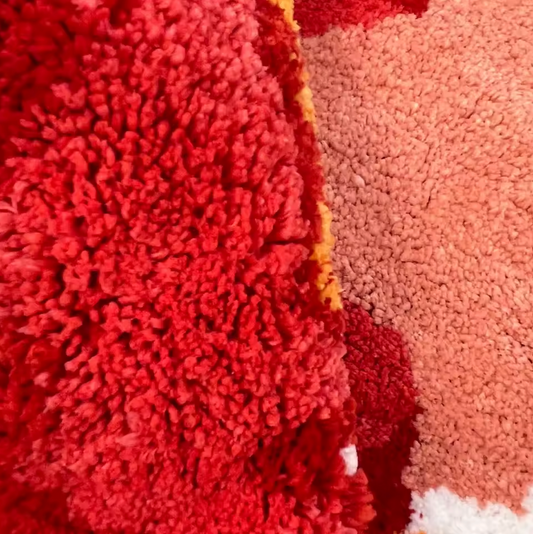 A close up of the Plantish Tomato Tufted Rug showcasing the thick and plush fibres in red, pink and white