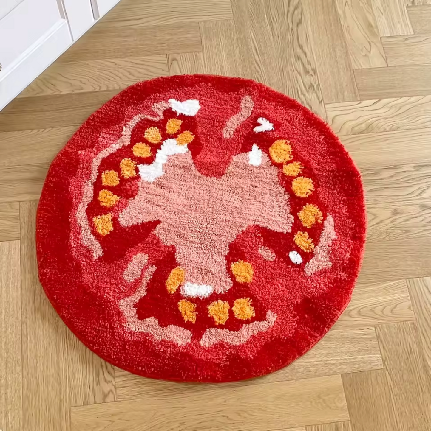 The Plantish Tomato Tufted Rug placed on a herringbone wooden floor, showing the red, yellow, white, and pink tomato slice design and plush material.
