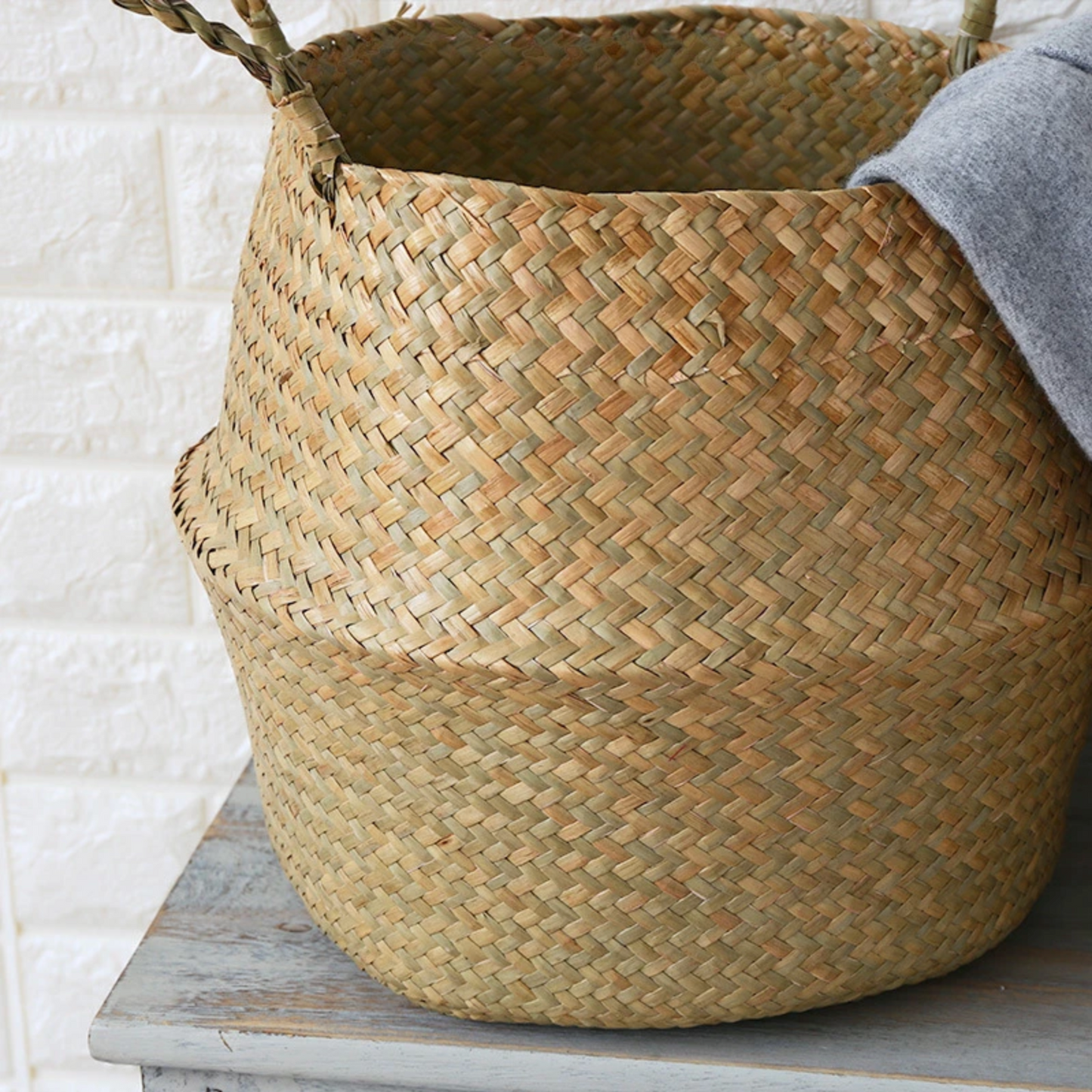 A close up of the Plantish Woven Wicker Basket fully extended, highlighting the detailed weave of the seagrass material. It is on a wooden table.