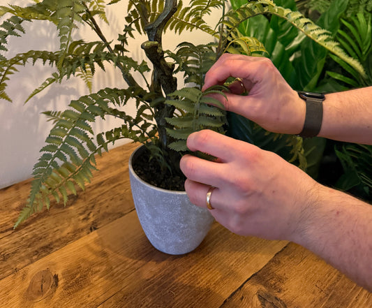 The fronds of an artificial fern being straightened and shaped