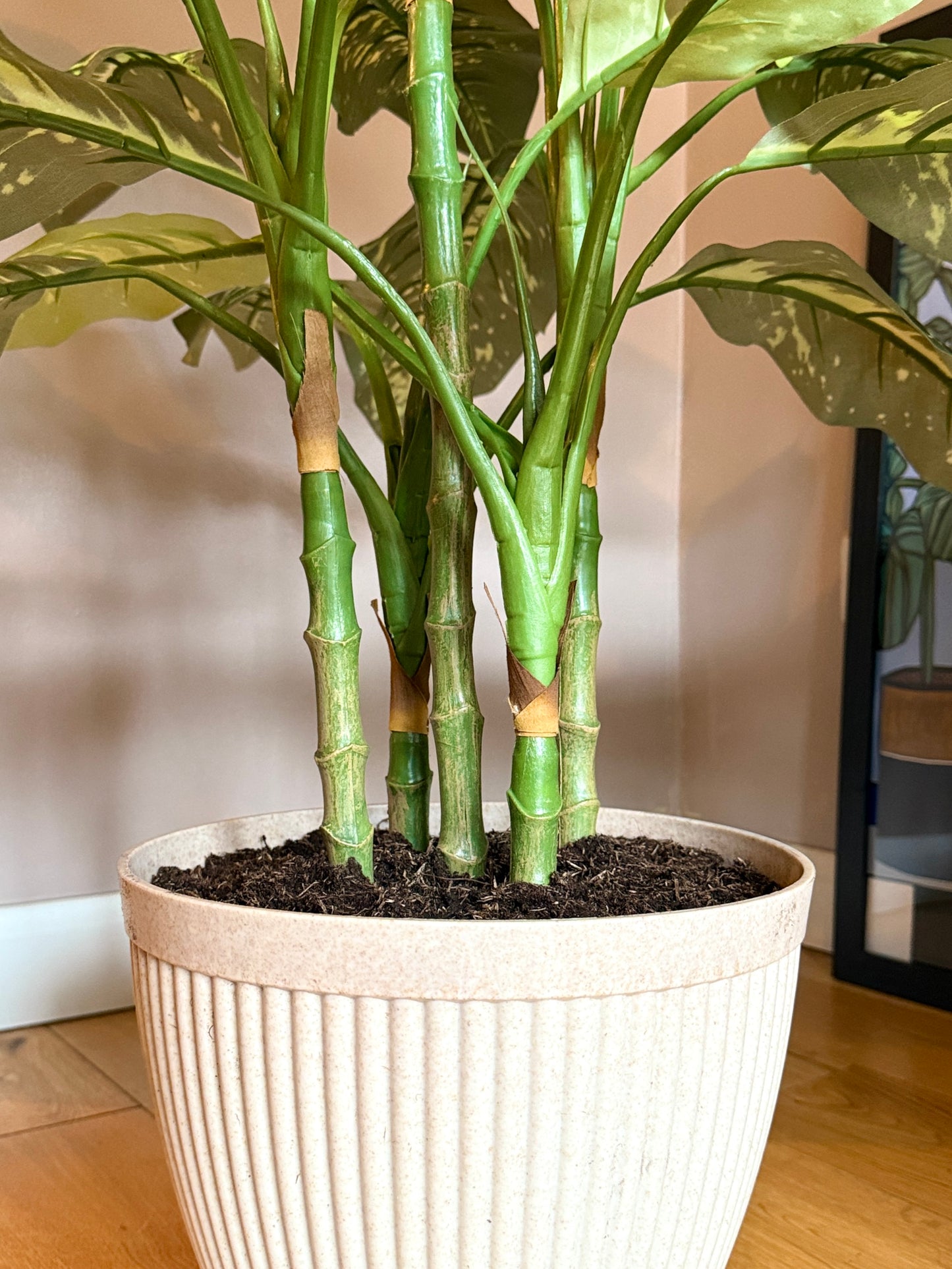 Detailed view of the Plantish artificial Aglaonema highlighting the lifelike stems and new emerging leaves, in a decorative cream pot.