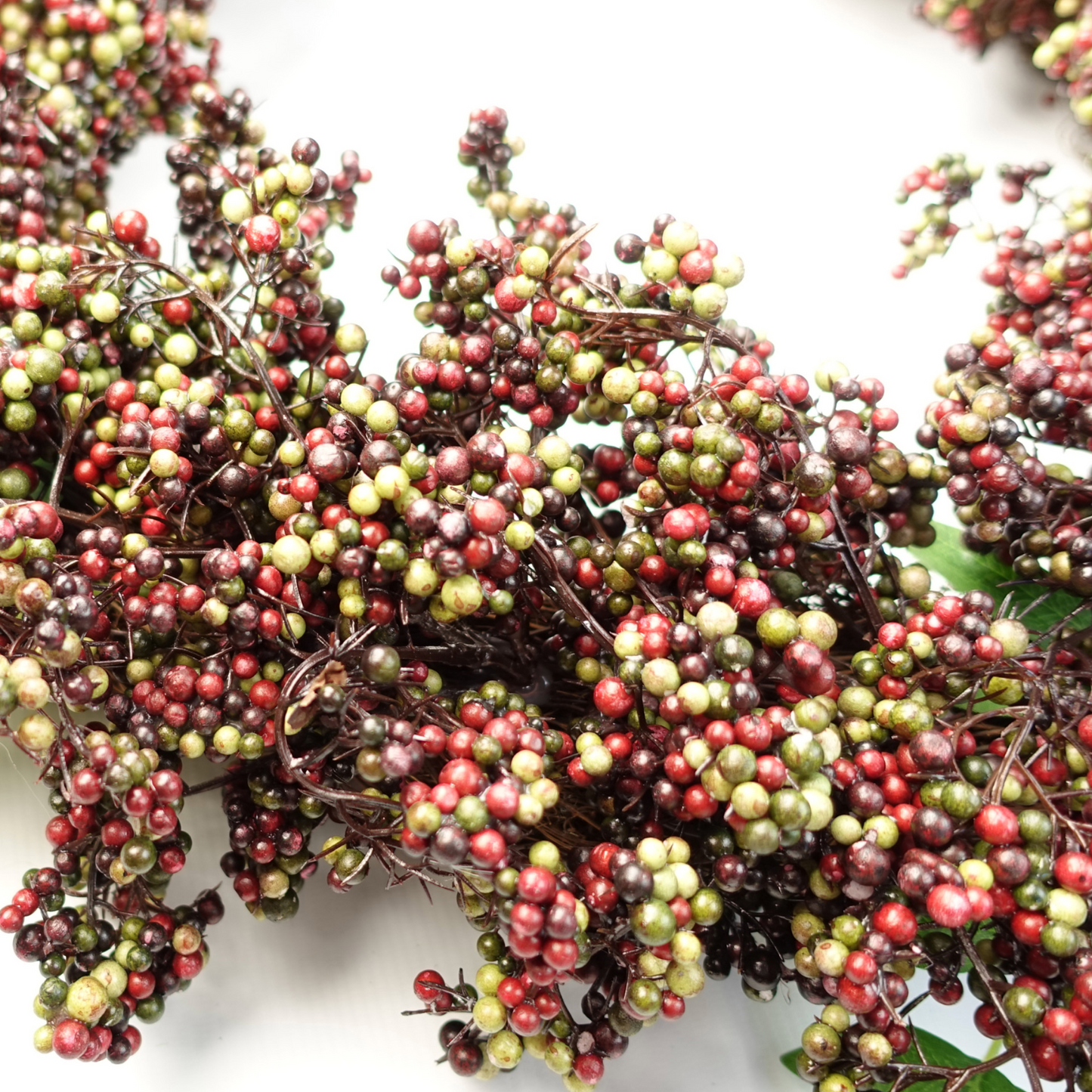 A mid-shot of the Plantish 55cm Black Berry Wreath, highlighting the black, green and red berries and green leaves.