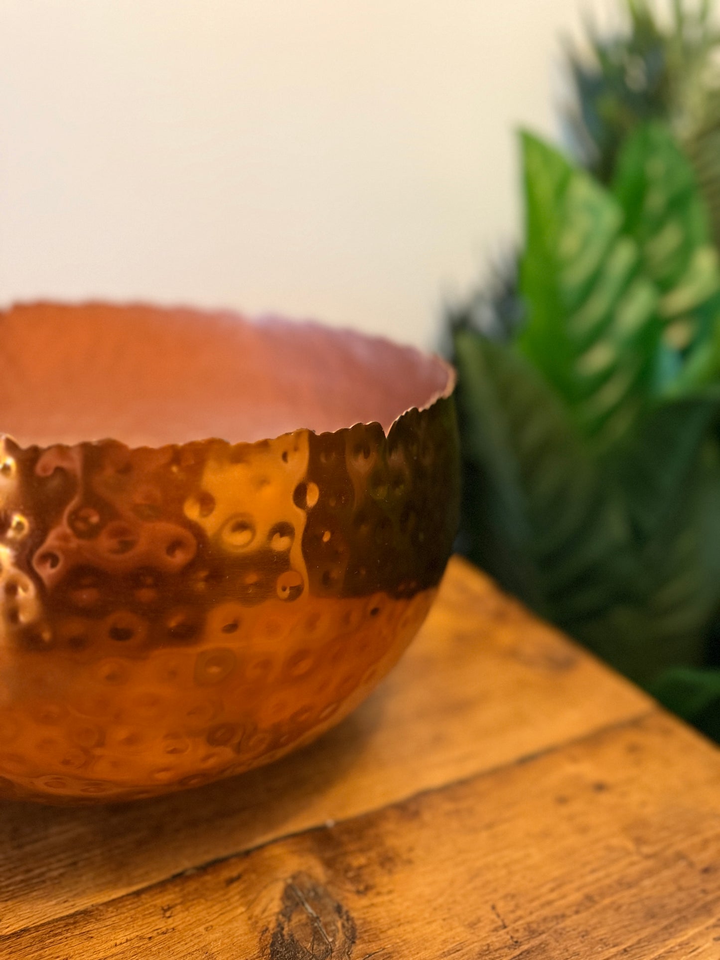 Close up of a large hammered copper-coloured metal planter, highlighting its textured surface.