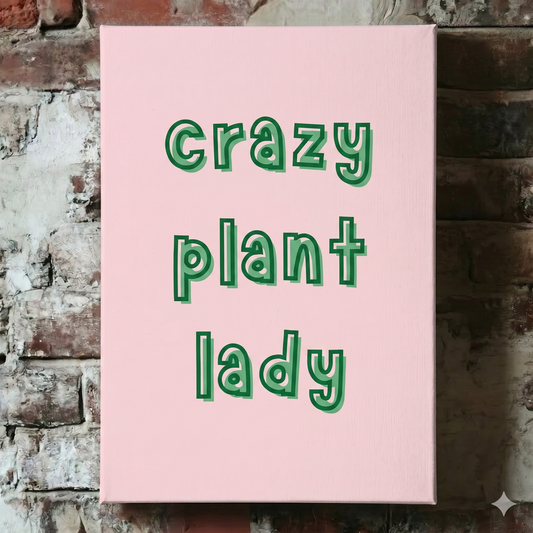 A Plantish canvas of the phrase "Crazy Plant Lady" in a green font with pink background, shown hanging on a red brick wall.
