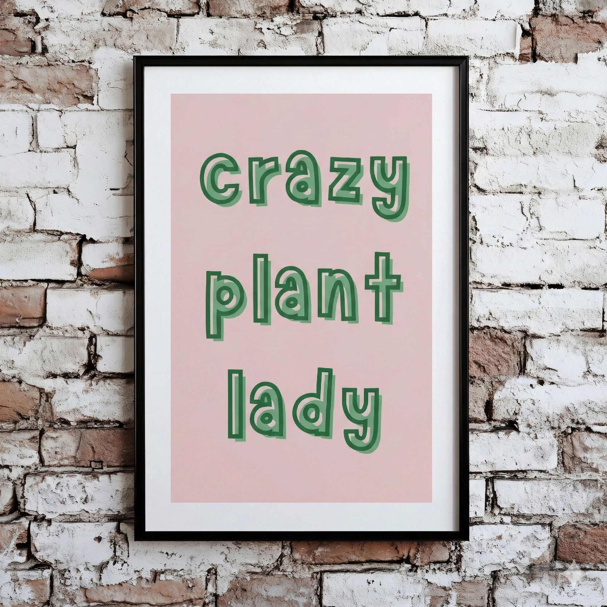 A Plantish print of the phrase "Crazy Plant Lady" in a green font with pink background, shown hanging on a brick wall.
