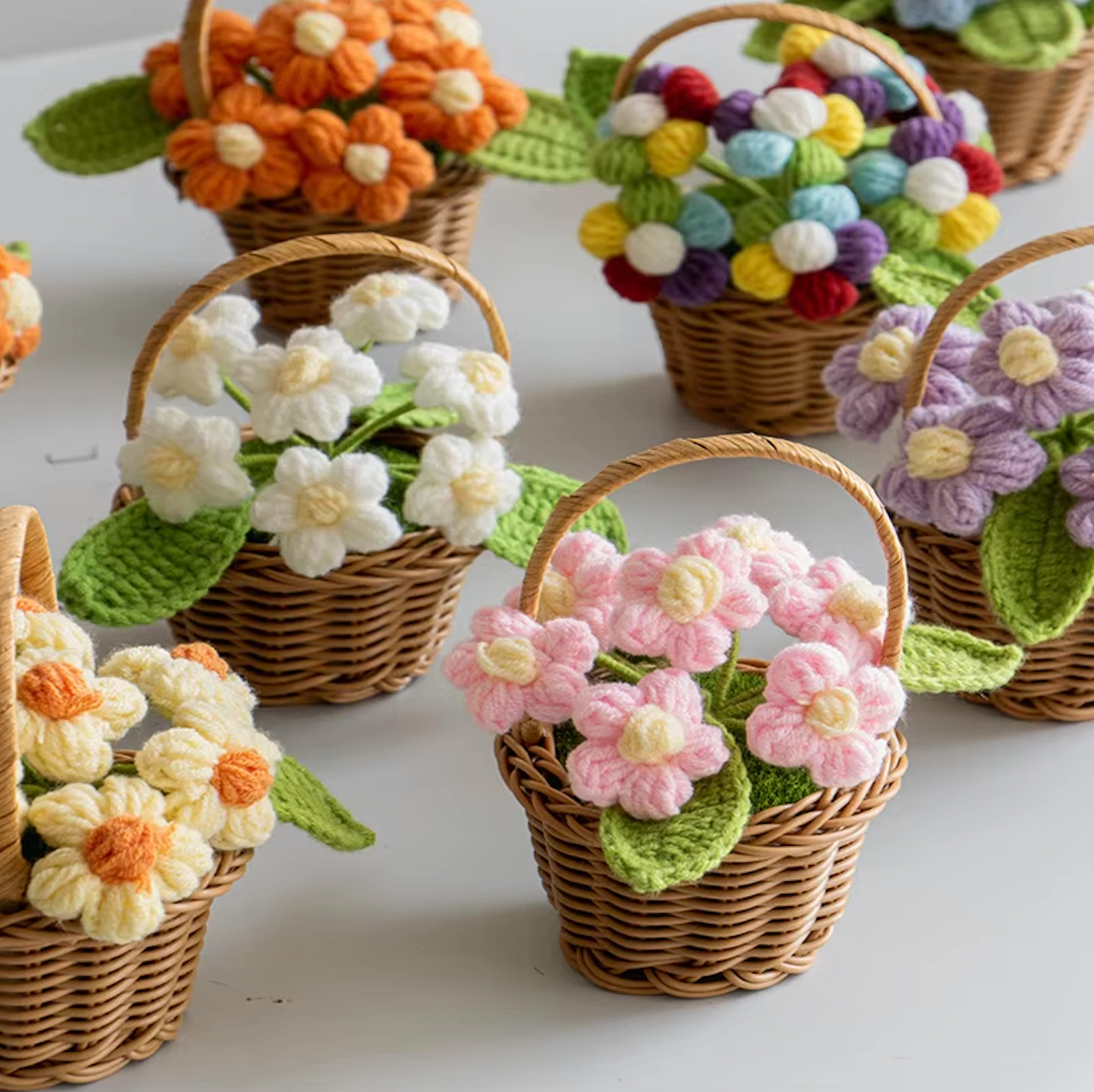 A close up image of the Plantish crocheted flower wicker baskets, placed on a white table. 
