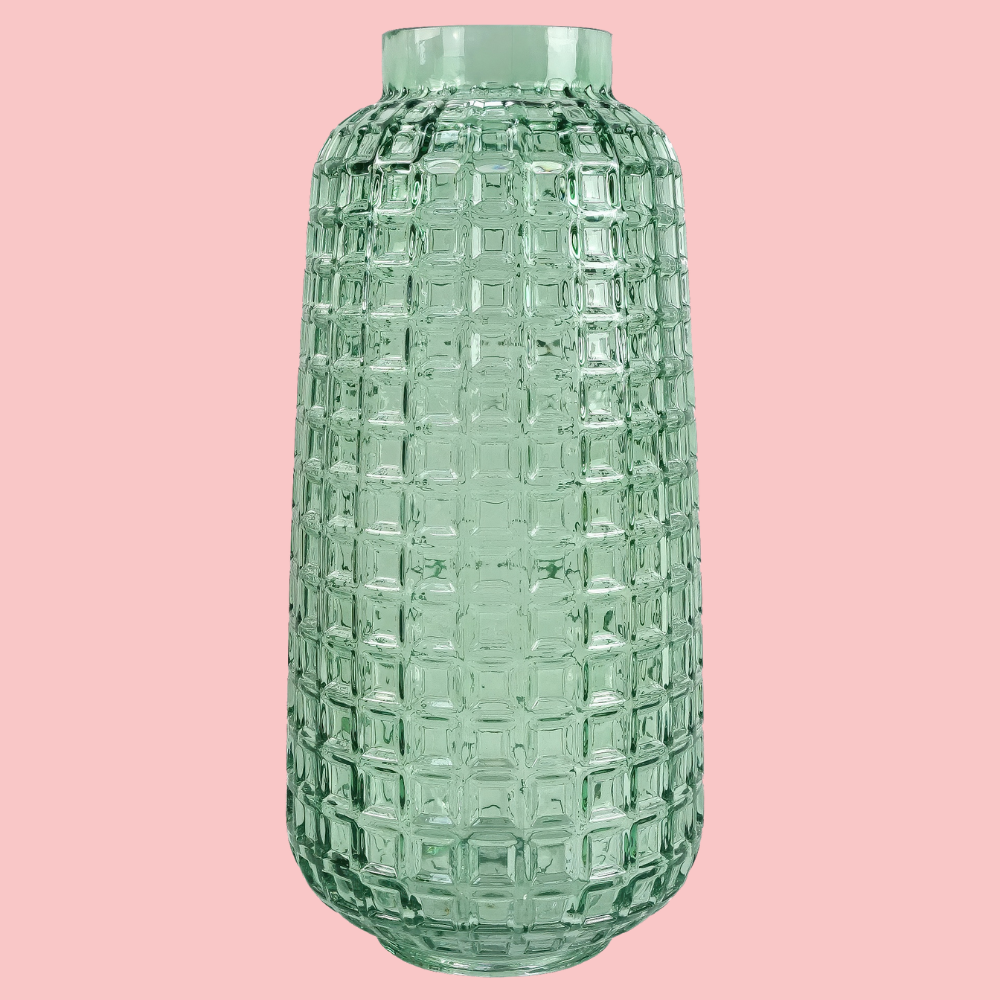 Front view of the Plantish Cube Vase, made of teal coloured glass with a textured cube design. Shown on a block pink background.