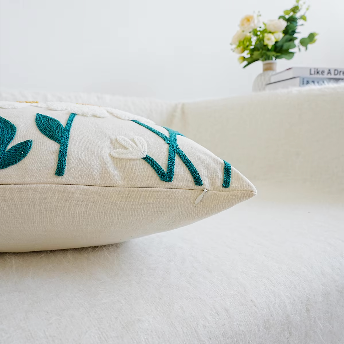 Close up of the Plantish Embroidered Daisy Cushion Cover resting on a white sofa, showing the hidden zip and embroidery.