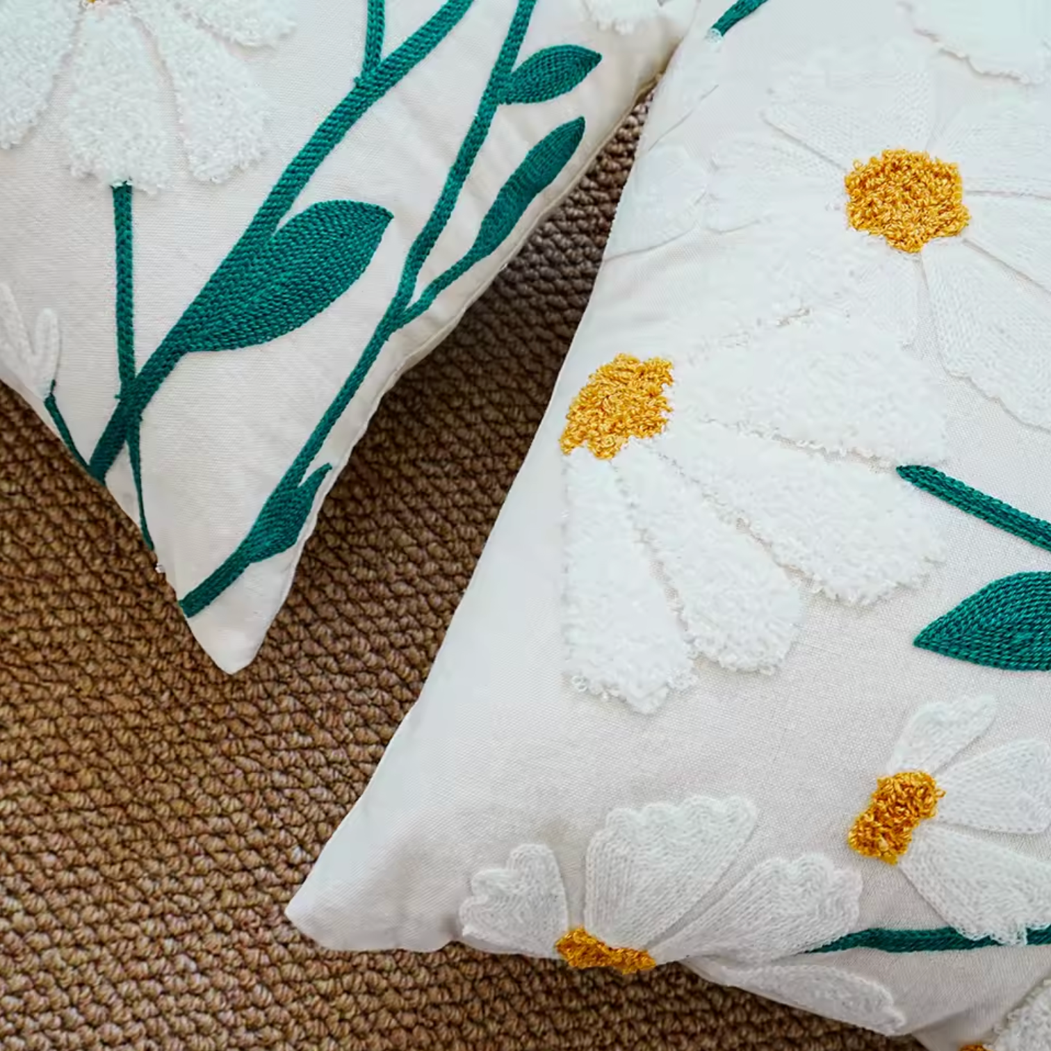 A close up of the Plantish Embroidered Daisy Cushion Cover, highlighting the detailed embroidery of the white daisy flowers and green stems.