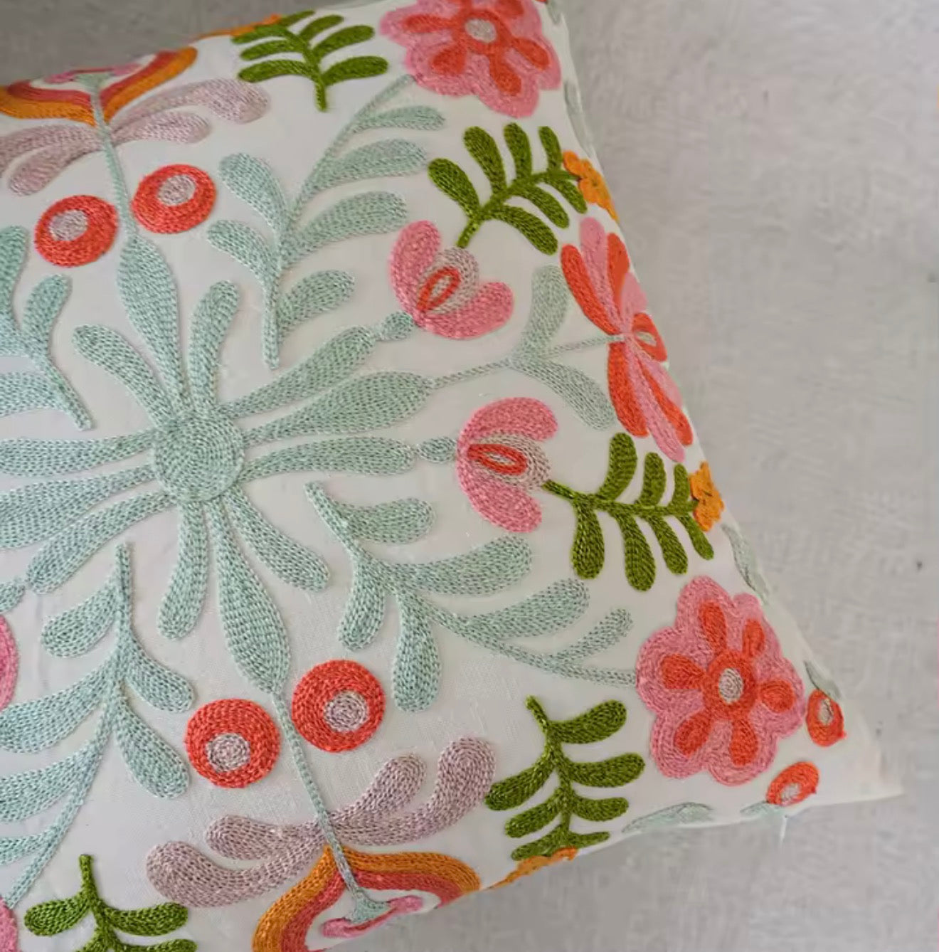 A close up of the Plantish Embroidered Sage Flower Cushion, highlighting the various stitched colours against a white background.