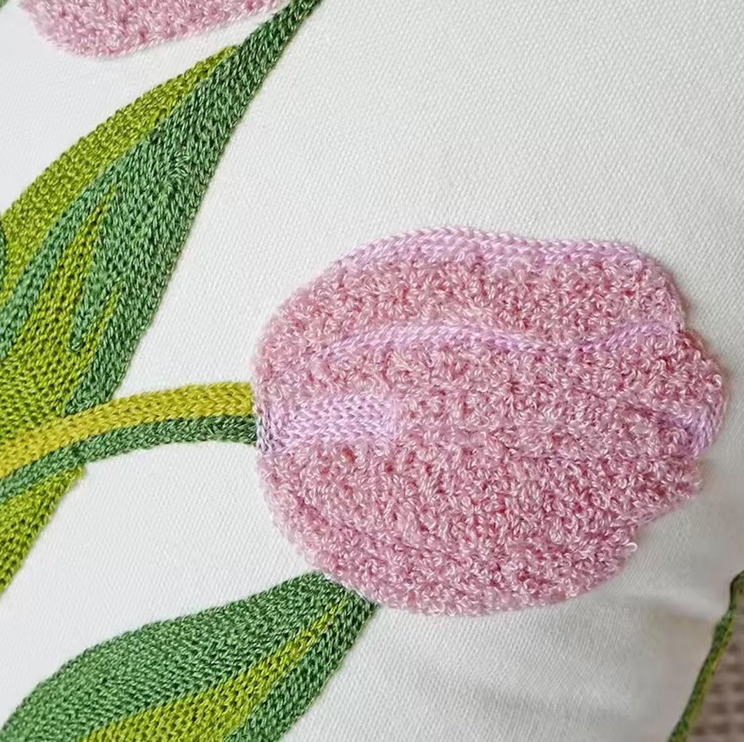 Close up of the Plantish Embroidered Tulip Cushion Cover in Pink, highlighting the detail of the embroidery on the leaves and flower. 