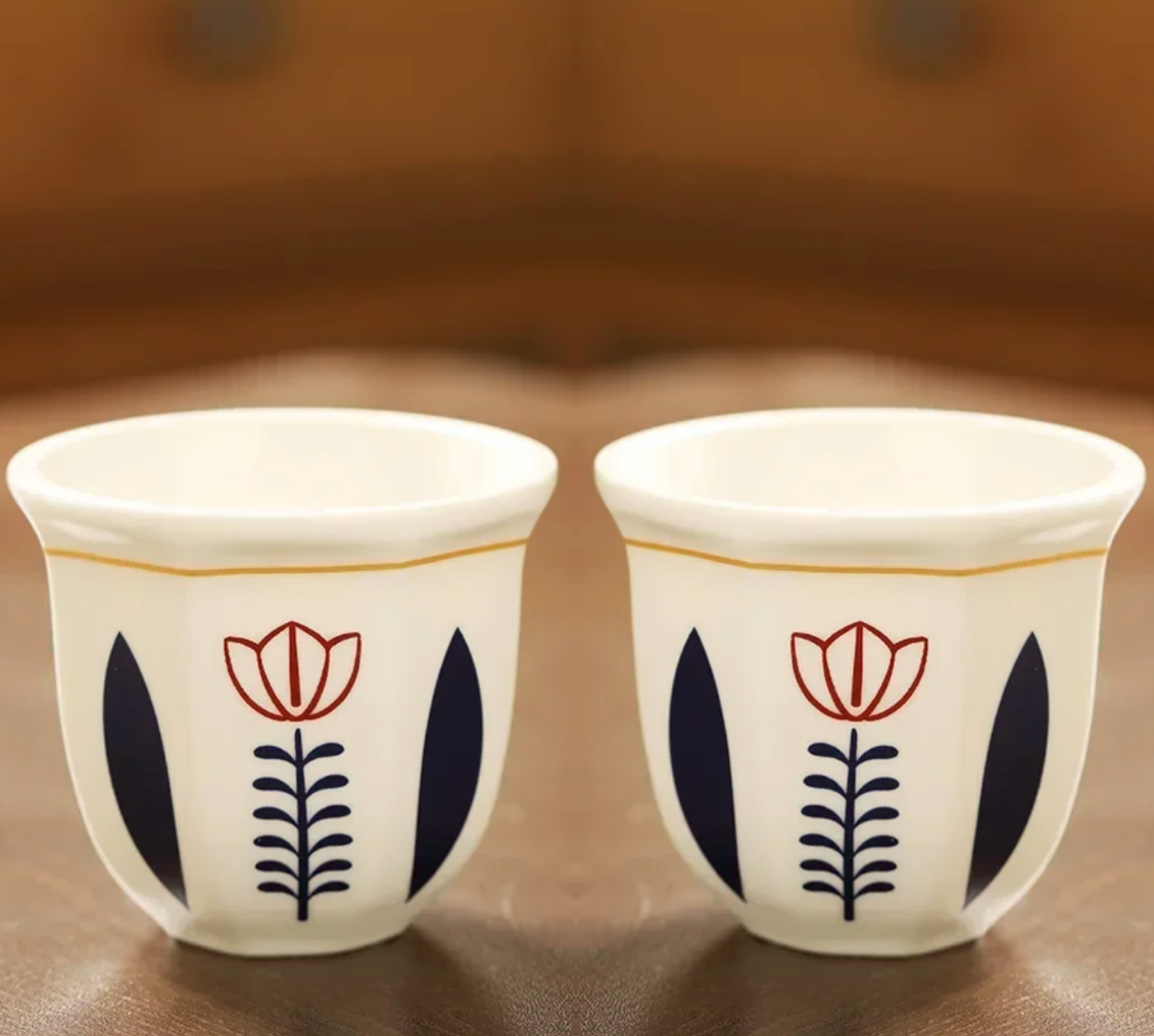 A close up of two Plantish Floral Espresso Cups in the Flower design, positioned on a brown wooden table.
