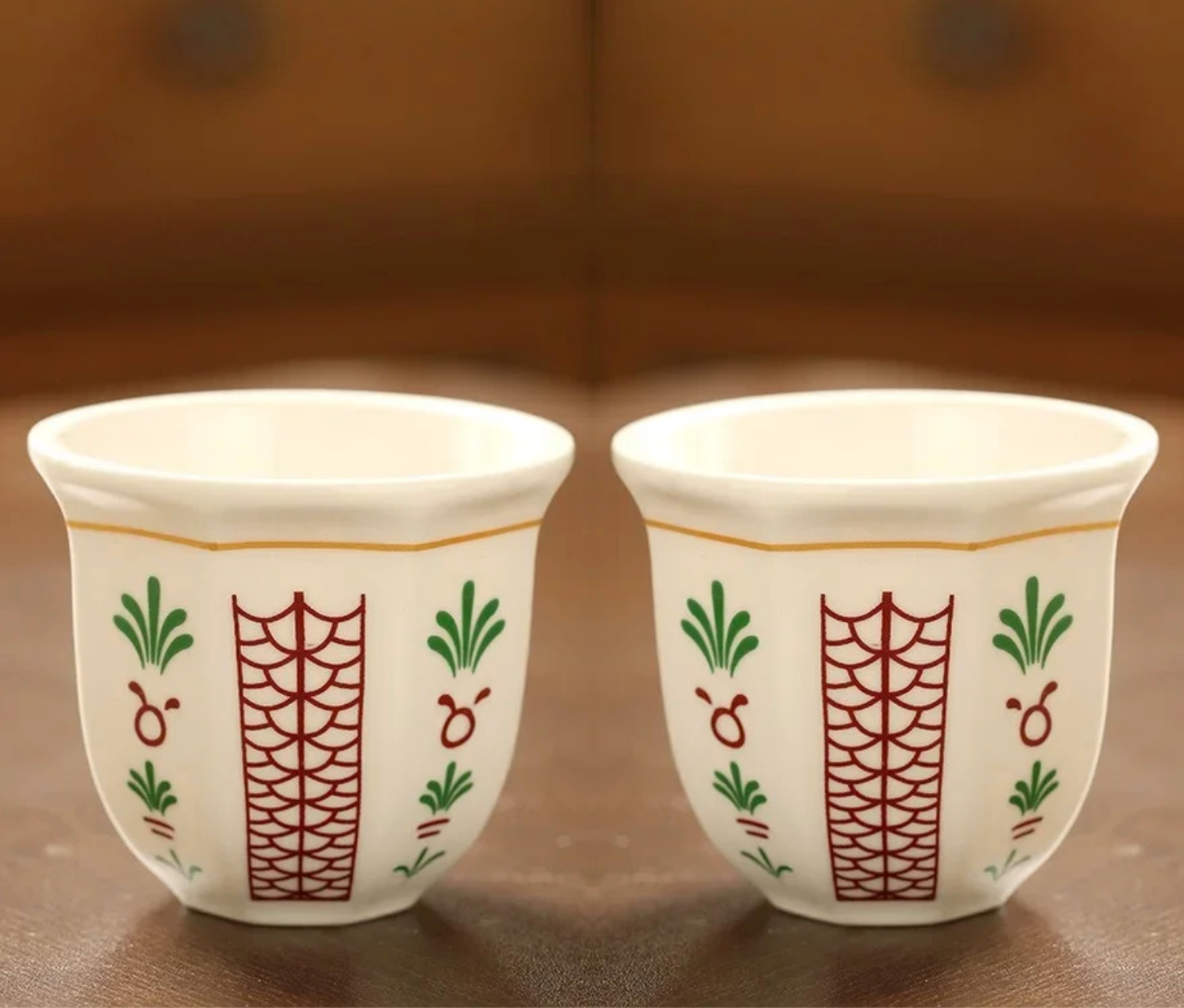 A close up of two Plantish Floral Espresso Cups in the Leaf design, positioned on a brown wooden table.
