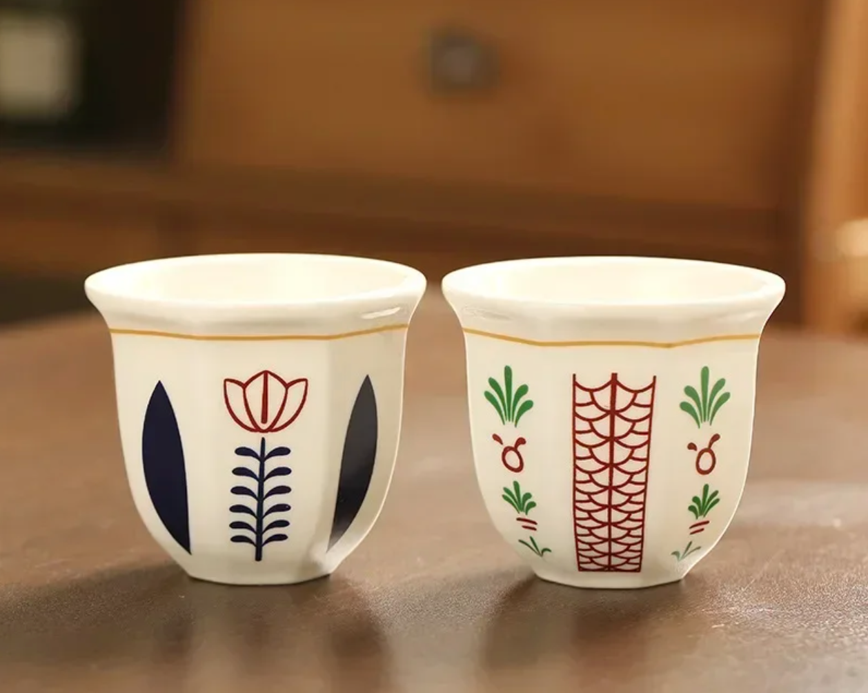 A close up of two Plantish Floral Espresso Cups with one in the Flower design and one in the Leaf design, positioned on a brown wooden table.