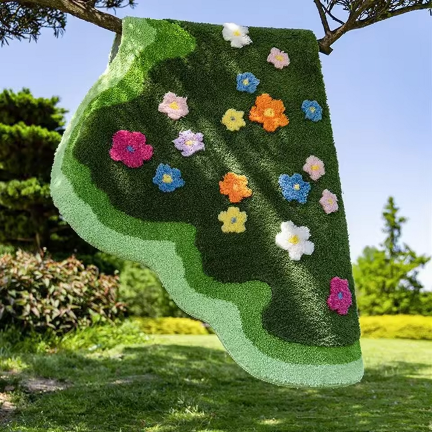 A close up of the Plantish Floral Tufted Rug which is hanging off the branch of a tree, outside in a lush green garden space. 