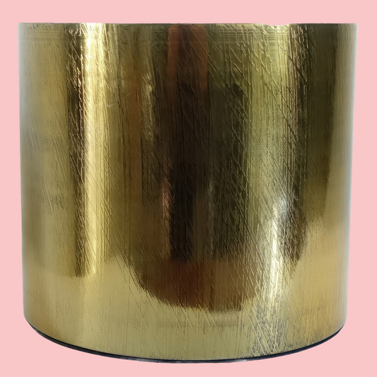 Side view of the Plantish Gold Etched Metal Pot, showing the geometric pattern on the sides. The pot is on a block pink background. 