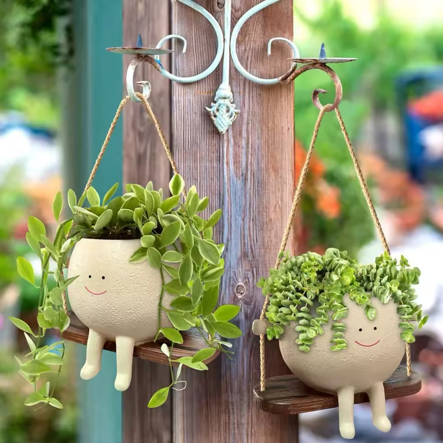 Two Plantish Happy Swing Plant Pot, hanging in from a metal bracket on a wooden post in a garden. There are a green succulents inside both pots.