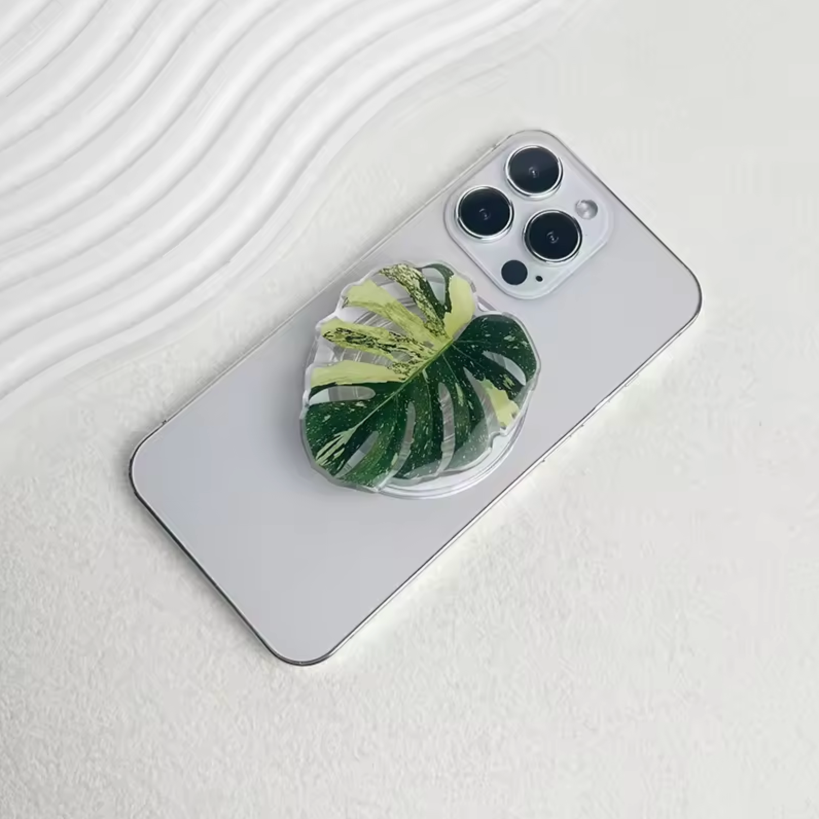The Plantish Monstera pop socket placed on the back of an iPhone. 