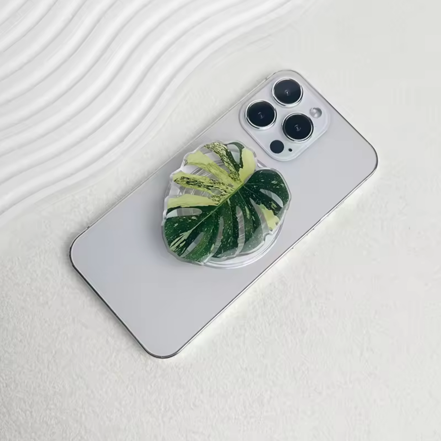 The Plantish Monstera pop socket placed on the back of an iPhone. 