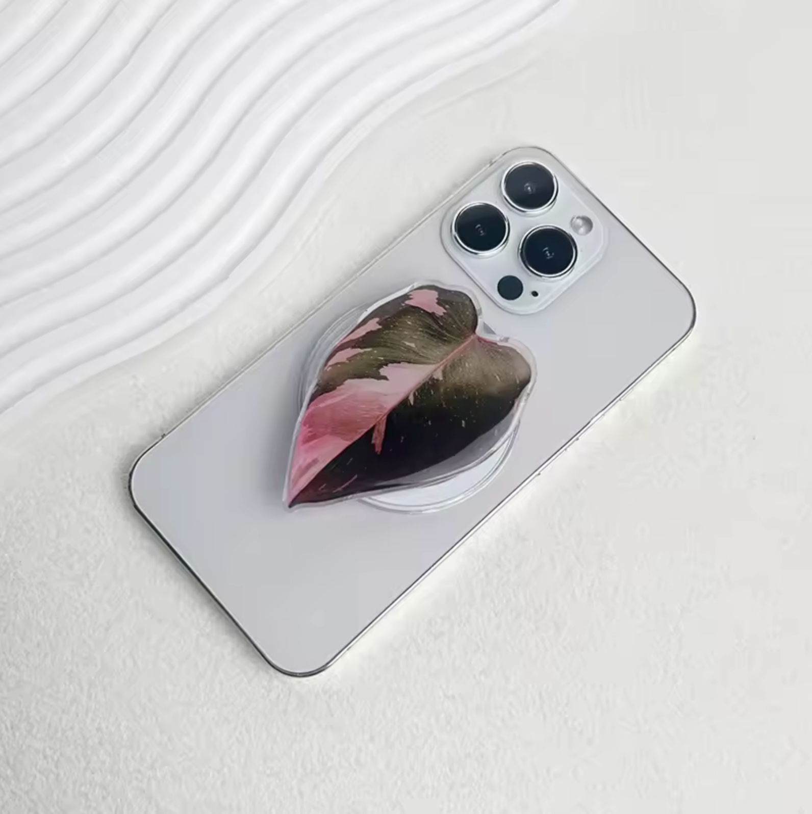 The Plantish Pink Princess pop socket attached to the back of a white iPhone.