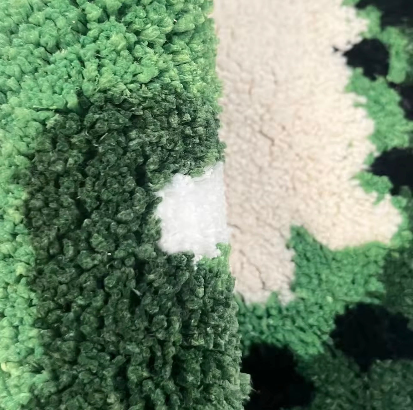 A close up of the Plantish Kiwi Tufted Rug, showing the shades of green, white and black in high detail. 