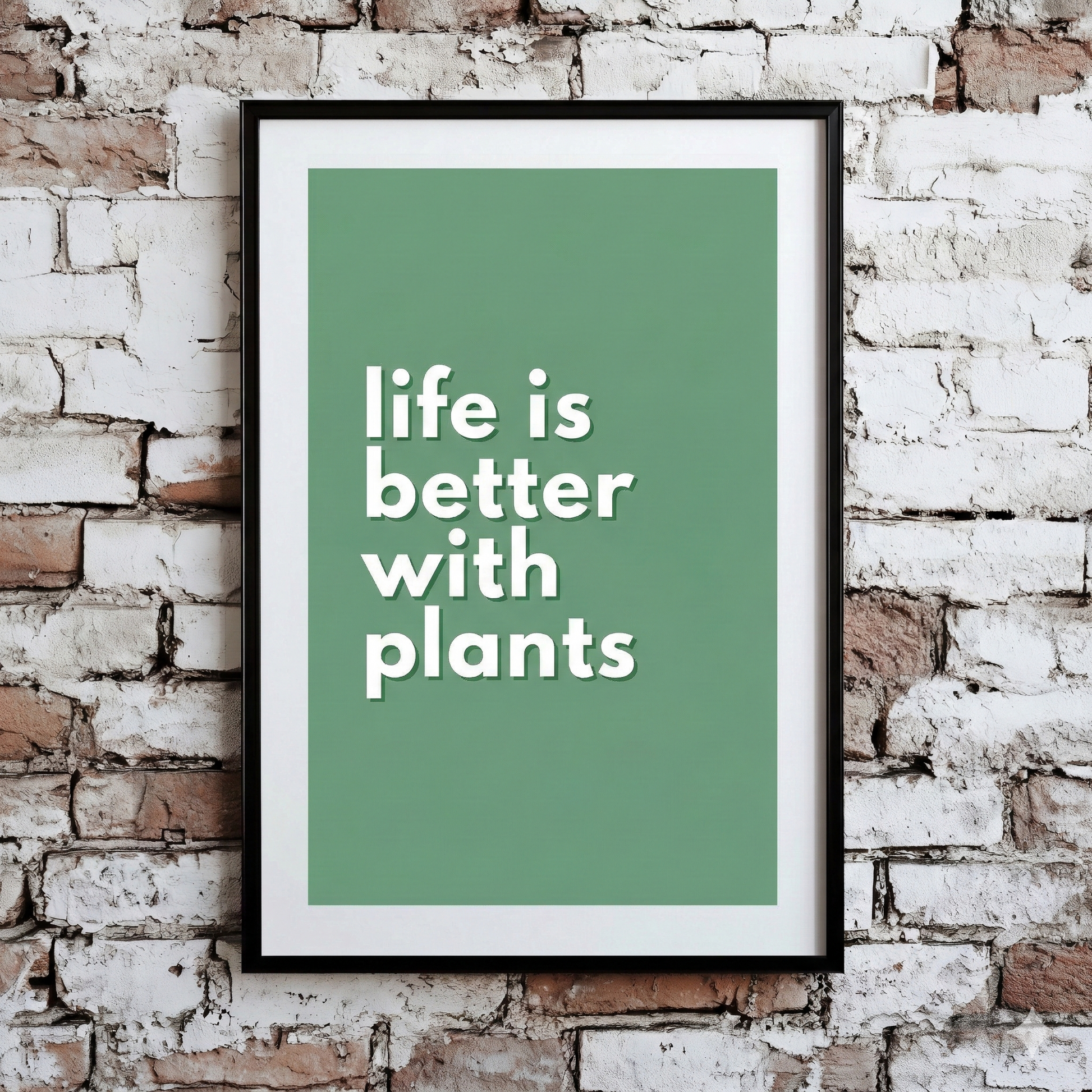 A Plantish print of the phrase "Life is Better With Plants" in a white font with green background, shown hanging on a brick wall.