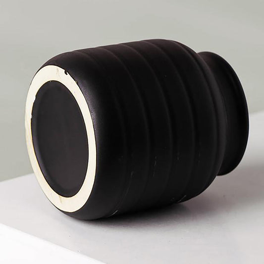 A bottom and side view of a small ceramic black vase with horizontal groove design. The neck of the vase is slimmer than the bottom.