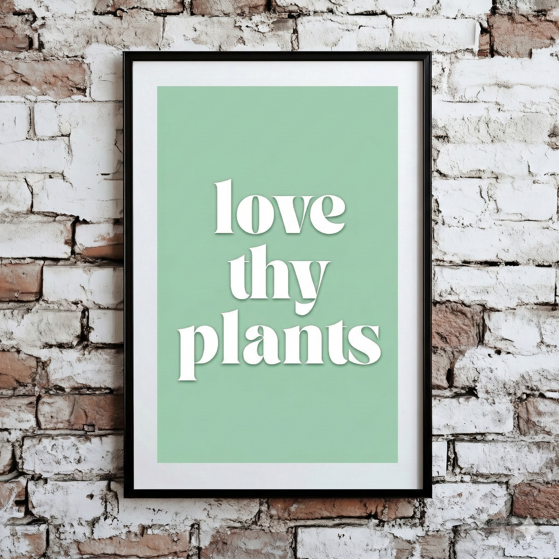 A Plantish print of the phrase "Love Thy Plants" in a white font with green background, shown hanging on a brick wall.